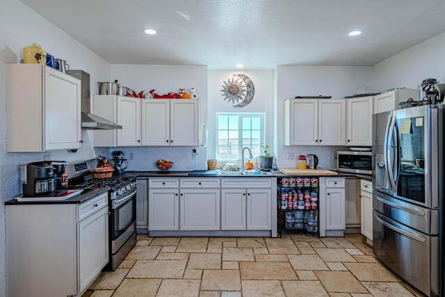 300 Thompson, Moriarty, NM 87035 - kitchen with stainless steel appliances, wall chimney range hood, stone tile flooring, dark countertops, and recessed lighting