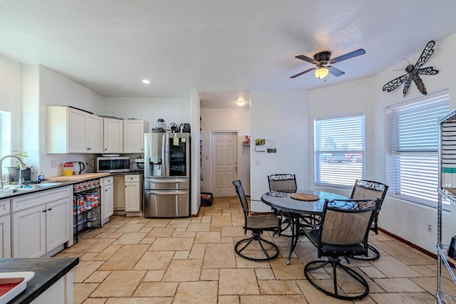 300 Thompson, Moriarty, NM 87035 - kitchen featuring appliances with stainless steel finishes, stone tile floors, ceiling fan, white cabinetry, and dark countertops