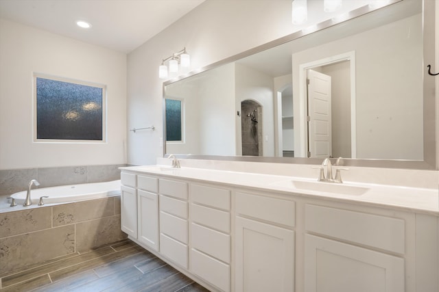 205 Silent Spring Dr NE, Rio Rancho, NM 87124 - bathroom with double vanity, a garden tub, and wood finished floors