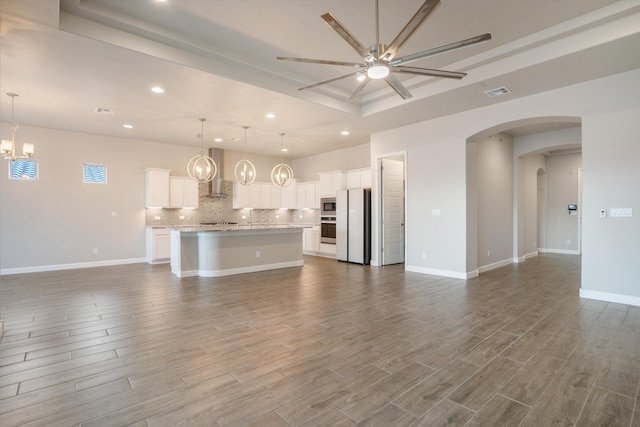 205 Silent Spring Dr NE, Rio Rancho, NM 87124 - unfurnished living room with a ceiling fan, a raised ceiling, recessed lighting, dark wood finished floors, and arched walkways
