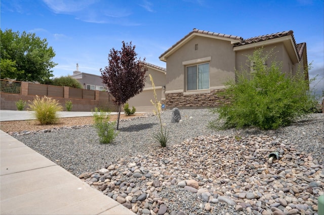 205 Silent Spring Dr NE, Rio Rancho, NM 87124 - view of side of home featuring stucco siding, stone siding, and a tiled roof