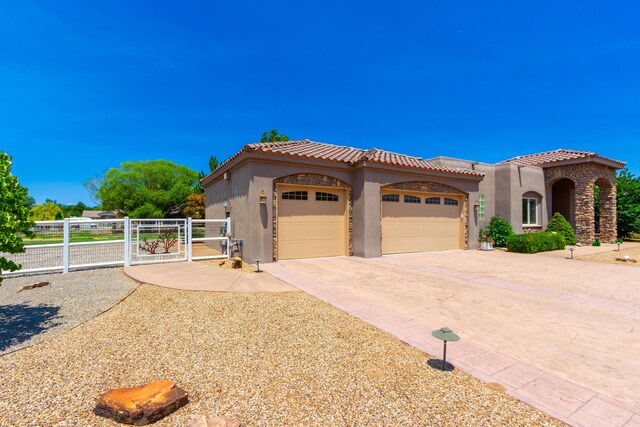 930 Titus Loop, Bosque Farms, NM 87068 - mediterranean / spanish home with stucco siding, a tiled roof, a garage, a gate, and concrete driveway