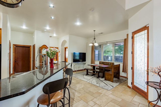 930 Titus Loop, Bosque Farms, NM 87068 - kitchen featuring arched walkways, stone tile floors, dark stone countertops, recessed lighting, and a kitchen bar