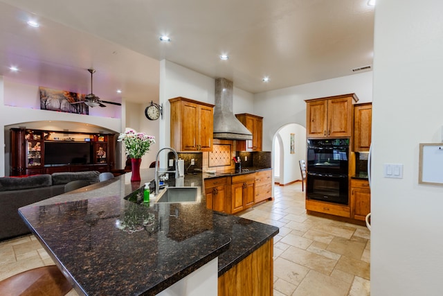 930 Titus Loop, Bosque Farms, NM 87068 - kitchen featuring wall chimney exhaust hood, arched walkways, black appliances, a ceiling fan, and stone tile floors