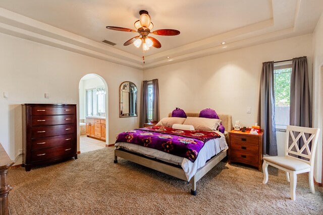 930 Titus Loop, Bosque Farms, NM 87068 - bedroom featuring a tray ceiling, light carpet, arched walkways, connected bathroom, and ceiling fan