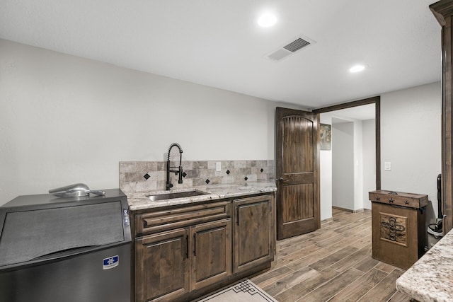91 Entrada Aragon Rd, Los Lunas, NM 87031 - kitchen with wood finished floors, dark brown cabinets, recessed lighting, backsplash, and light stone counters