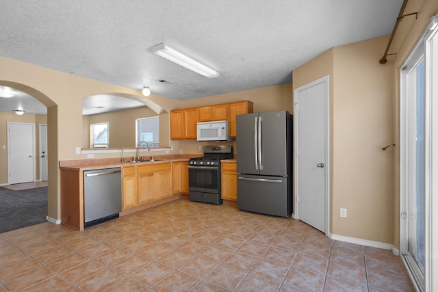 1944 Sierra Norte Loop NE, Rio Rancho, NM 87144 - kitchen with stainless steel appliances, light countertops, arched walkways, a textured ceiling, and light tile patterned floors