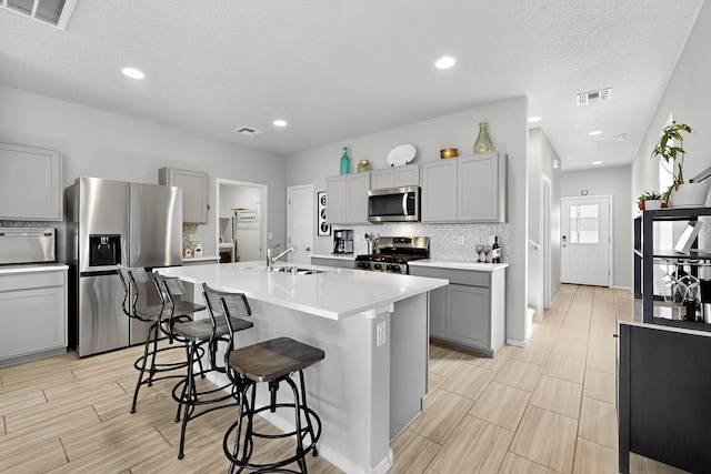 4823 Blackburn Rd NE, Rio Rancho, NM 87144 - kitchen featuring stainless steel appliances, gray cabinets, a kitchen breakfast bar, light countertops, and a kitchen island with sink