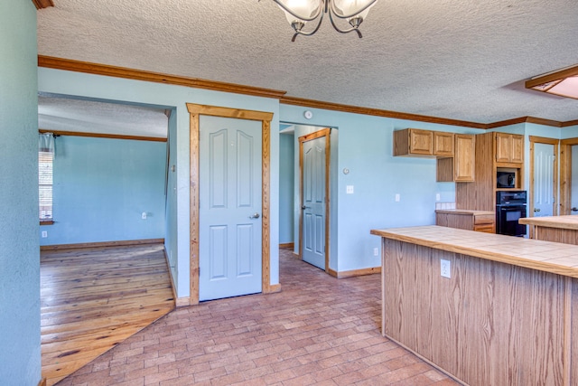 10 Quail Run Rd, Tijeras, NM 87059 - kitchen featuring stainless steel microwave, black oven, brick floors, a textured ceiling, and a chandelier
