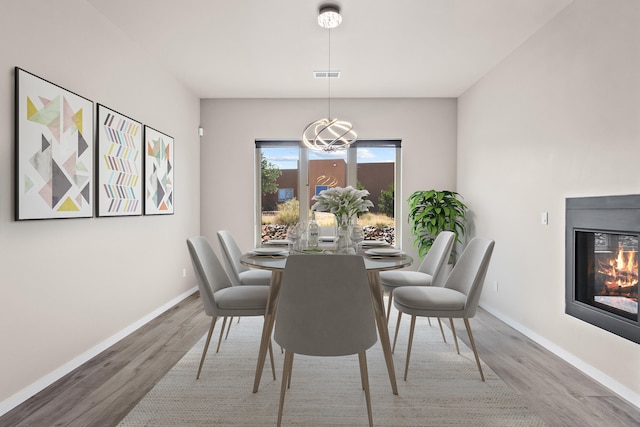 7 Aztec Ct, Placitas, NM 87043 - dining area with wood finished floors, a chandelier, and a glass covered fireplace