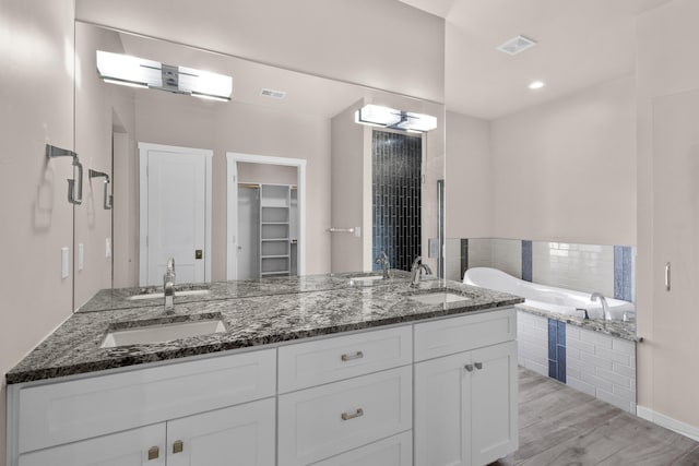 7 Aztec Ct, Placitas, NM 87043 - full bathroom with double vanity, tiled tub, wood finished floors, and a walk in closet