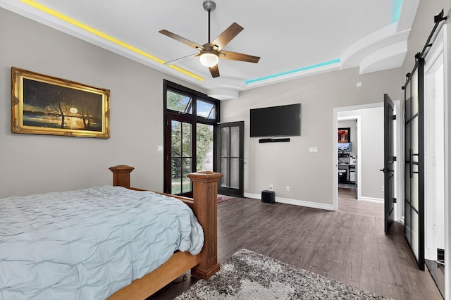 6205 Peachtree Pl NE, Albuquerque, NM 87111 - bedroom featuring a barn door, a raised ceiling, wood finished floors, access to outside, and ceiling fan