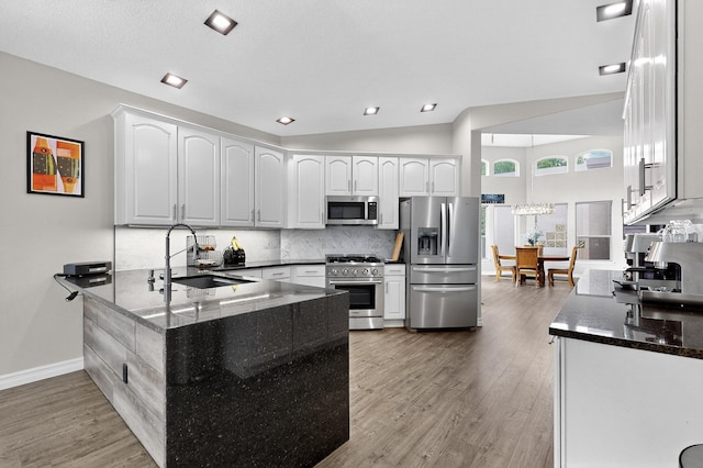 6205 Peachtree Pl NE, Albuquerque, NM 87111 - kitchen with appliances with stainless steel finishes, a peninsula, light wood-type flooring, tasteful backsplash, and lofted ceiling