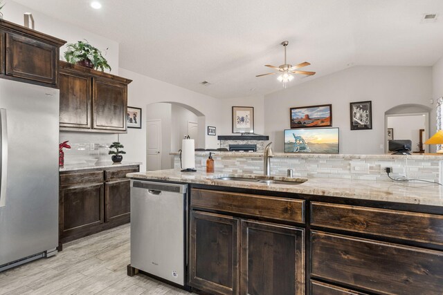 2660 Firewheel Ave SW, Los Lunas, NM 87031 - kitchen featuring appliances with stainless steel finishes, a ceiling fan, tasteful backsplash, light wood finished floors, and light stone countertops