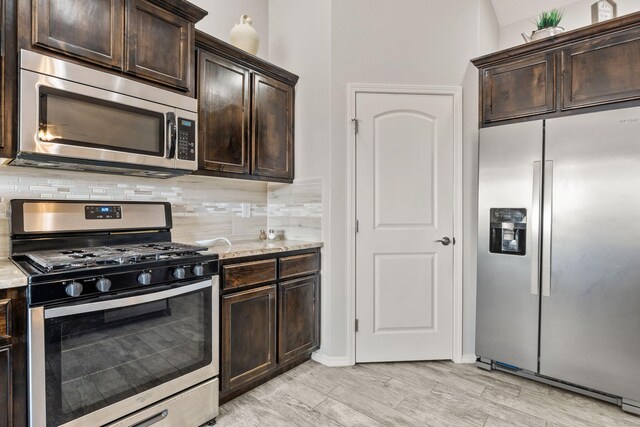 2660 Firewheel Ave SW, Los Lunas, NM 87031 - kitchen with stainless steel appliances, tasteful backsplash, dark brown cabinets, and light stone counters