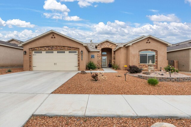 2660 Firewheel Ave SW, Los Lunas, NM 87031 - view of front of property with stucco siding, concrete driveway, stone siding, and an attached garage
