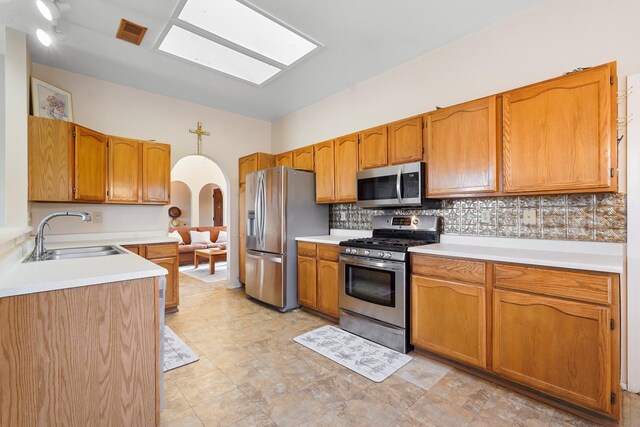 6268 Apache Plume Rd NE, Rio Rancho, NM 87144 - kitchen featuring appliances with stainless steel finishes, decorative backsplash, light countertops, arched walkways, and brown cabinetry