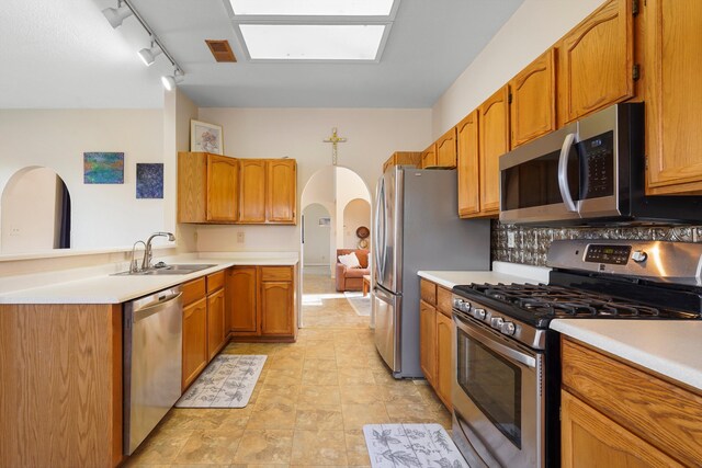 6268 Apache Plume Rd NE, Rio Rancho, NM 87144 - kitchen with stainless steel appliances, arched walkways, light countertops, and brown cabinets