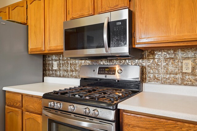 6268 Apache Plume Rd NE, Rio Rancho, NM 87144 - kitchen with stainless steel appliances, light countertops, backsplash, and brown cabinetry