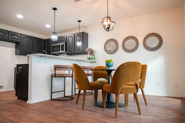 4441 Kellia Ln NE, Albuquerque, NM 87111 - kitchen with stainless steel microwave, wood finished floors, pendant lighting, a chandelier, and a peninsula