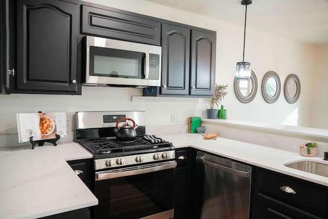 4441 Kellia Ln NE, Albuquerque, NM 87111 - kitchen featuring stainless steel appliances, dark cabinets, decorative light fixtures, and light stone counters