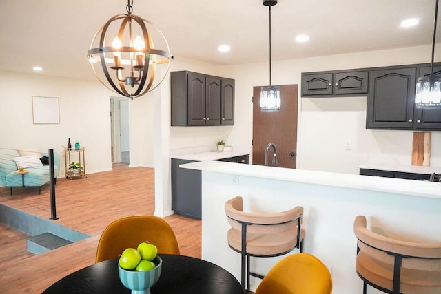 4441 Kellia Ln NE, Albuquerque, NM 87111 - kitchen featuring light wood-type flooring, a chandelier, light countertops, a breakfast bar, and recessed lighting