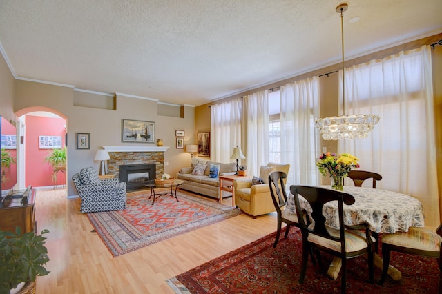 6749 Kelly Ann Rd NE, Albuquerque, NM 87109 - living room featuring ornamental molding, wood finished floors, arched walkways, a textured ceiling, and a fireplace