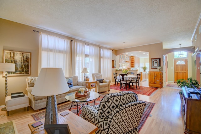 6749 Kelly Ann Rd NE, Albuquerque, NM 87109 - living area featuring arched walkways, light wood-type flooring, a textured ceiling, ornamental molding, and a chandelier