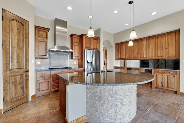 2413 Desert View Rd NE, Rio Rancho, NM 87144 - kitchen featuring stainless steel appliances, wall chimney exhaust hood, arched walkways, brown cabinetry, and tasteful backsplash