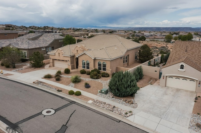 2413 Desert View Rd NE, Rio Rancho, NM 87144 - view of front facade featuring driveway, an attached garage, stucco siding, a residential view, and a tiled roof