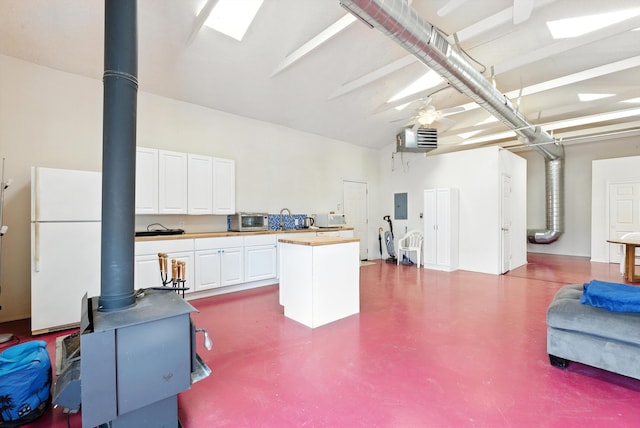 6205 Darlene Pl SW, Albuquerque, NM 87105 - garage featuring freestanding refrigerator, electric panel, a wood stove, and a ceiling fan