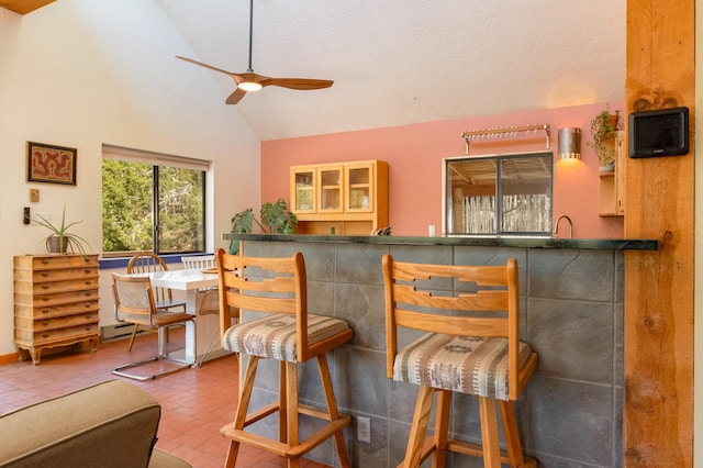 23 Cooper Rd, Cedar Crest, NM 87008 - dining space featuring a ceiling fan, brick patterned floors, wet bar, a baseboard radiator, and high vaulted ceiling