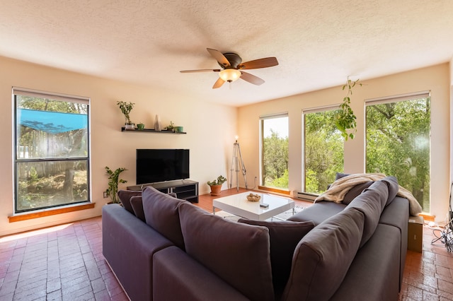 23 Cooper Rd, Cedar Crest, NM 87008 - living room featuring ceiling fan, a baseboard radiator, a textured ceiling, and brick flooring