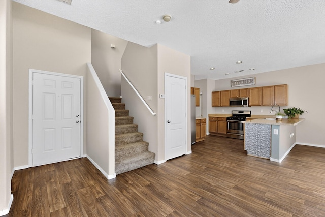 2353 Cortina Loop SE, Rio Rancho, NM 87124 - kitchen with stainless steel appliances, light countertops, dark wood-style floors, a textured ceiling, and a peninsula