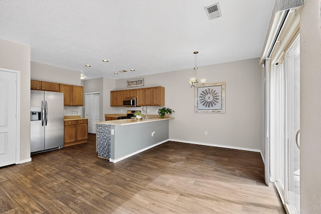 2353 Cortina Loop SE, Rio Rancho, NM 87124 - kitchen featuring appliances with stainless steel finishes, brown cabinets, a peninsula, light countertops, and dark wood finished floors