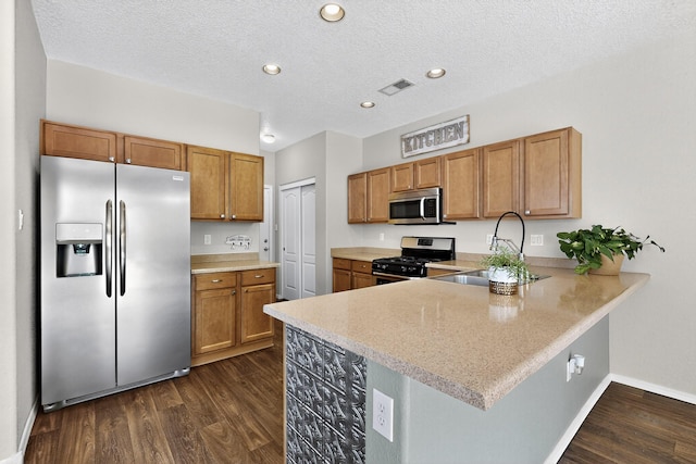 2353 Cortina Loop SE, Rio Rancho, NM 87124 - kitchen featuring appliances with stainless steel finishes, dark wood-style flooring, brown cabinetry, a peninsula, and recessed lighting