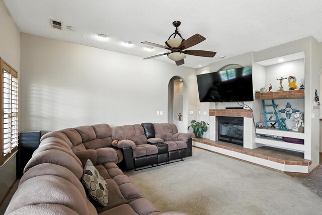 8500 Clarks Fork Rd NW, Albuquerque, NM 87120 - living area with arched walkways, ceiling fan, a tile fireplace, and carpet flooring