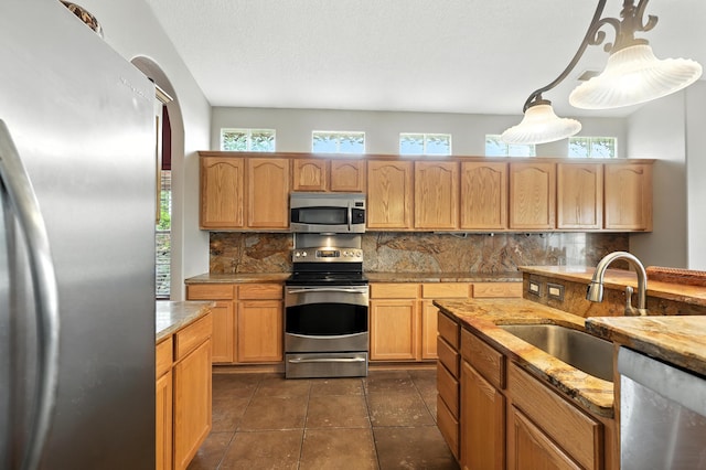 8500 Clarks Fork Rd NW, Albuquerque, NM 87120 - kitchen with appliances with stainless steel finishes, backsplash, light stone countertops, hanging light fixtures, and dark tile patterned flooring