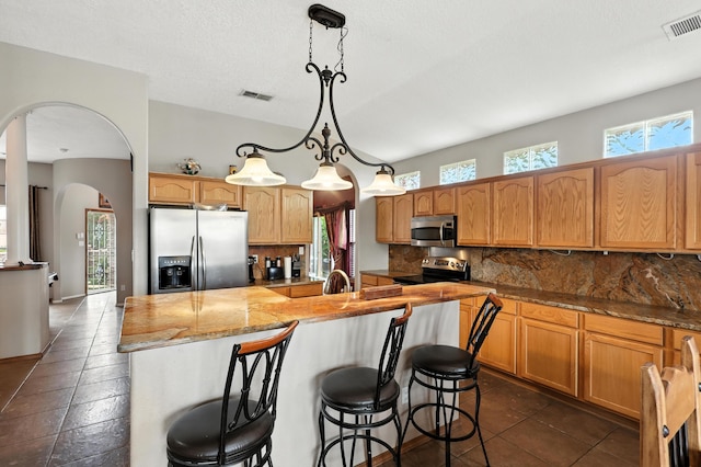 8500 Clarks Fork Rd NW, Albuquerque, NM 87120 - kitchen featuring stainless steel appliances, arched walkways, tasteful backsplash, and a center island