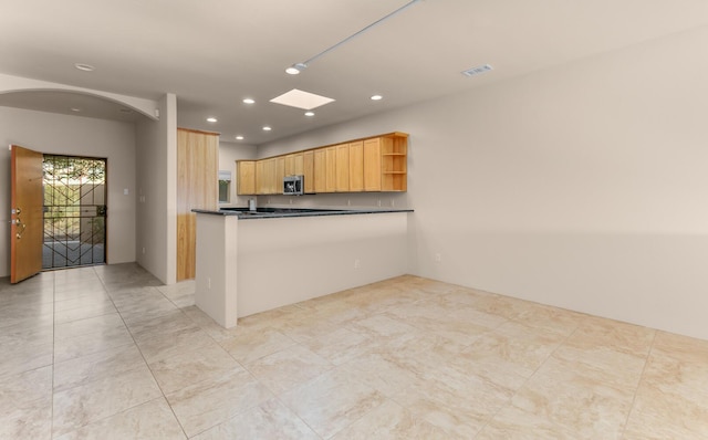 31 Wind Rd NW, Albuquerque, NM 87120 - kitchen featuring stainless steel microwave, recessed lighting, open shelves, dark countertops, and a skylight