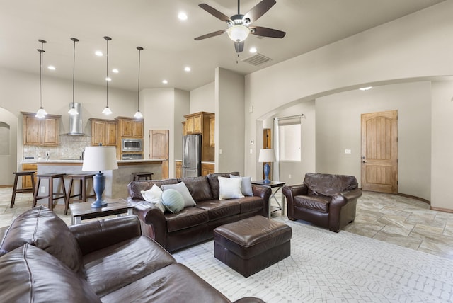 9844 Cameron St NW, Albuquerque, NM 87114 - living room featuring arched walkways, a ceiling fan, light stone finish floors, recessed lighting, and a high ceiling