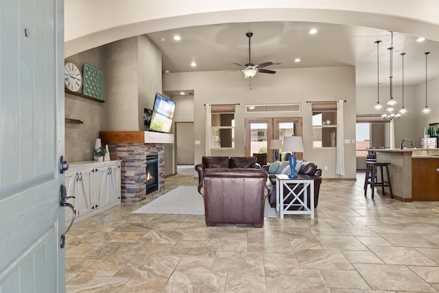9844 Cameron St NW, Albuquerque, NM 87114 - living room with arched walkways, ceiling fan, a fireplace, stone tile floors, and a towering ceiling