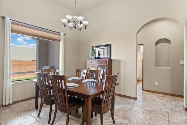 9844 Cameron St NW, Albuquerque, NM 87114 - dining space featuring a chandelier, arched walkways, stone tile floors, and high vaulted ceiling
