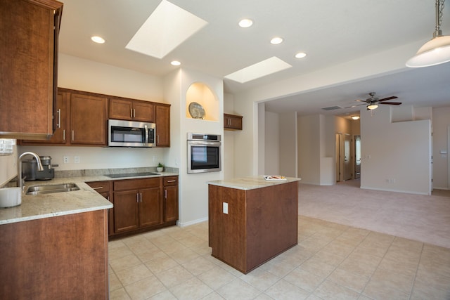 827 Purple Aster Dr, Bernalillo, NM 87004 - kitchen with stainless steel appliances, light colored carpet, a skylight, light stone counters, and a center island
