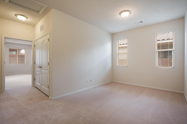 827 Purple Aster Dr, Bernalillo, NM 87004 - spare room featuring light carpet, healthy amount of natural light, a textured ceiling, and attic access