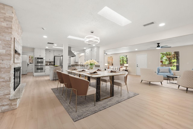 697 W W Meadowlark Ln, Corrales, NM 87048 - dining space featuring a skylight, a fireplace, light wood-style floors, recessed lighting, and ceiling fan