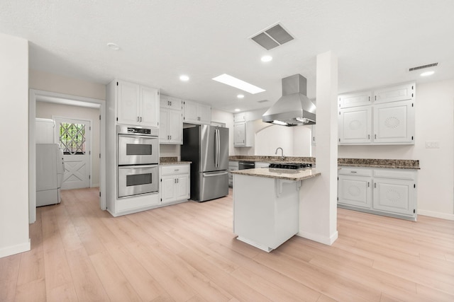 697 W W Meadowlark Ln, Corrales, NM 87048 - kitchen with appliances with stainless steel finishes, island exhaust hood, a peninsula, washer / clothes dryer, and white cabinets