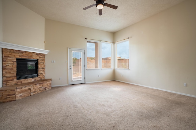 5485 Roosevelt Loop NE, Rio Rancho, NM 87144 - unfurnished living room with ceiling fan, carpet, a stone fireplace, and a textured ceiling