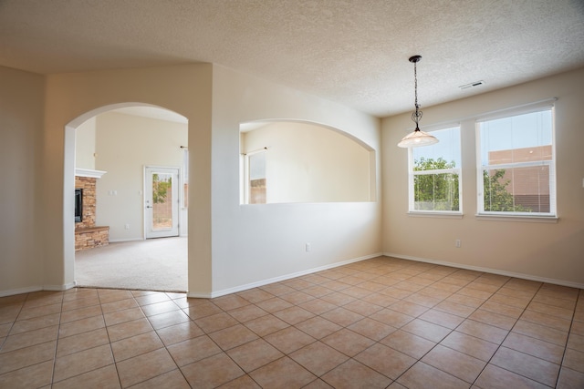 5485 Roosevelt Loop NE, Rio Rancho, NM 87144 - tiled spare room with a fireplace with raised hearth, a textured ceiling, carpet, and arched walkways