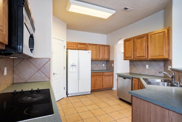 5485 Roosevelt Loop NE, Rio Rancho, NM 87144 - kitchen with black appliances, backsplash, brown cabinetry, arched walkways, and light tile patterned flooring